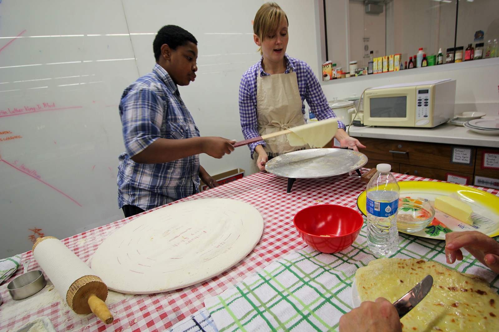  two people making flatbread on a portable griddle