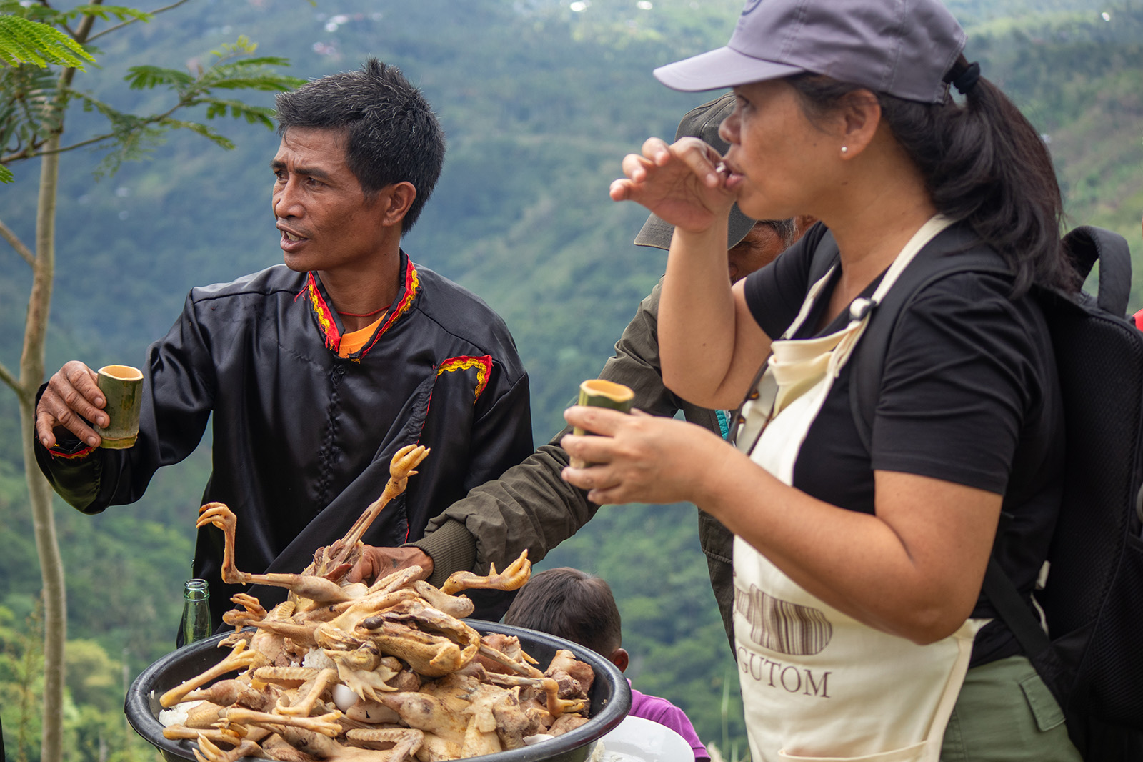 Peterson and locals on a green hilltop with drinks and meat